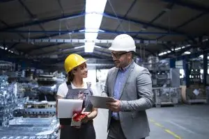 supervisor y trabajador discuten los resultados de producción y la nueva estrategia en la nave industrial de la fábrica